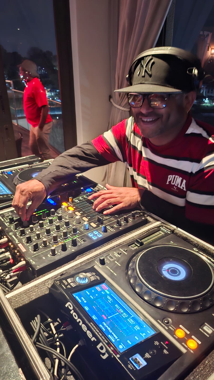 Entertainworx DJ smiling behind Pioneer DJ decks at an evening event
